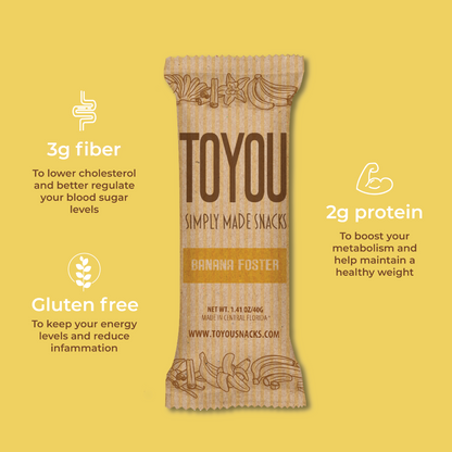 Front view: Banana Foster ToYou Snack bar in artistic paper wrapper next to icons: (3g Fiber, Gluten free, 2g Protein) on a yellow background.